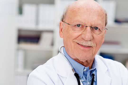 Älterer Arzt lächelt in die Kamera