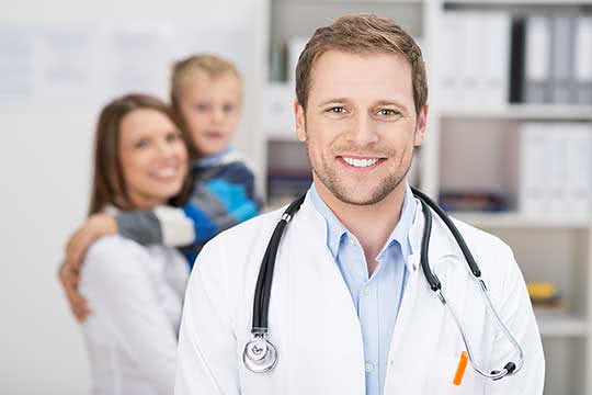 Junger Arzt mit Stethoskop lächelt in die Kamera